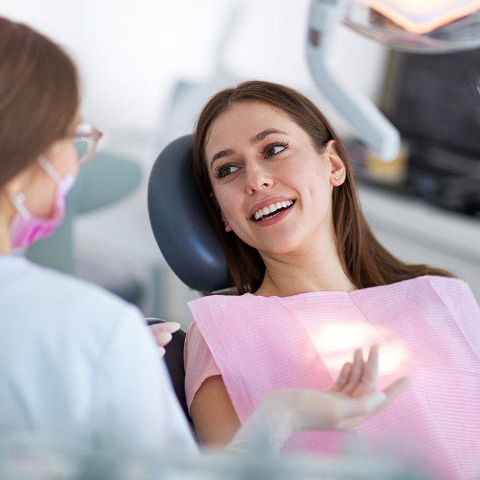 Woman in dental chair talking to her dentist