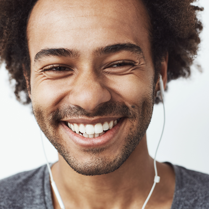 Man wearing earbuds and smiling with white teeth