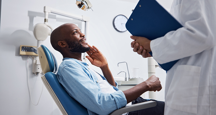 Man holding his cheek while talking to his emergency dentist in Wilmington