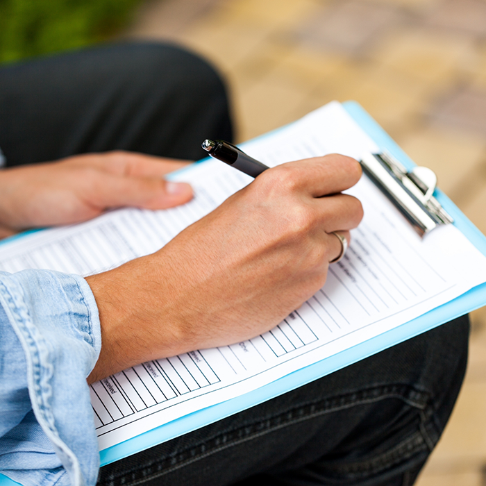 Person filling out paperwork on a clipboard