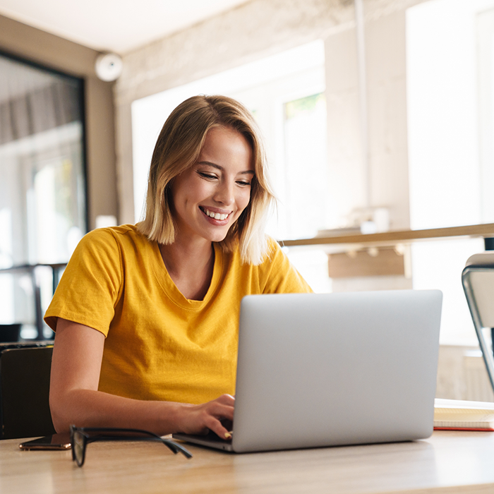 Woman smiling while sitting at a table and using her laptop