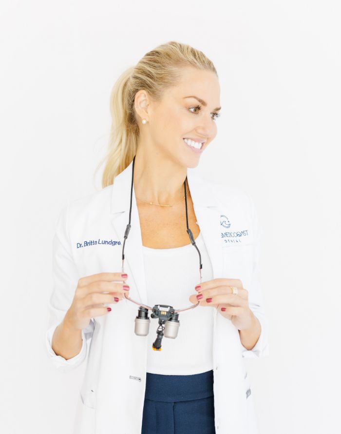 Doctor Lundgren in a white lab coat holding dental binoculars