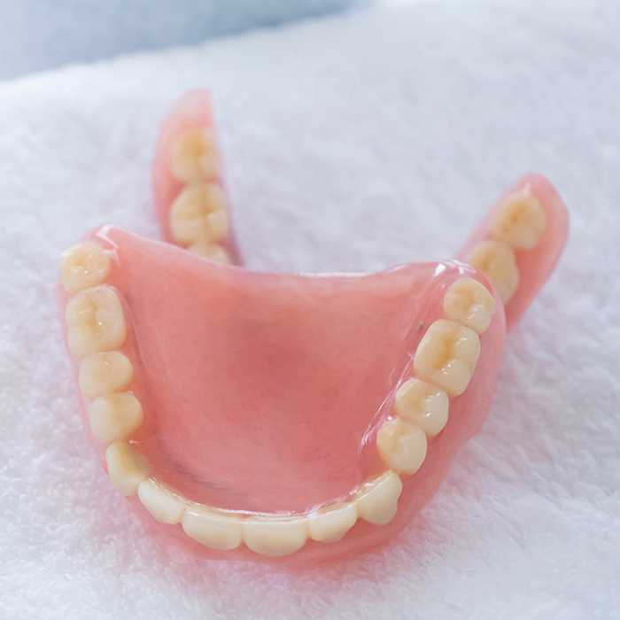 Two dentures resting on a soft white surface