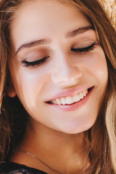 Young woman smiling with her eyes closed