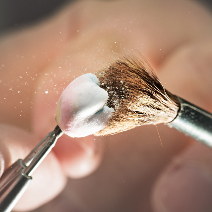 Close up of a small brush dusting off a dental crown