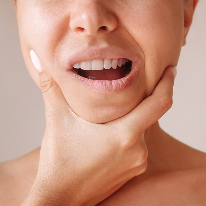 Person holding the sides of their jaw in pain